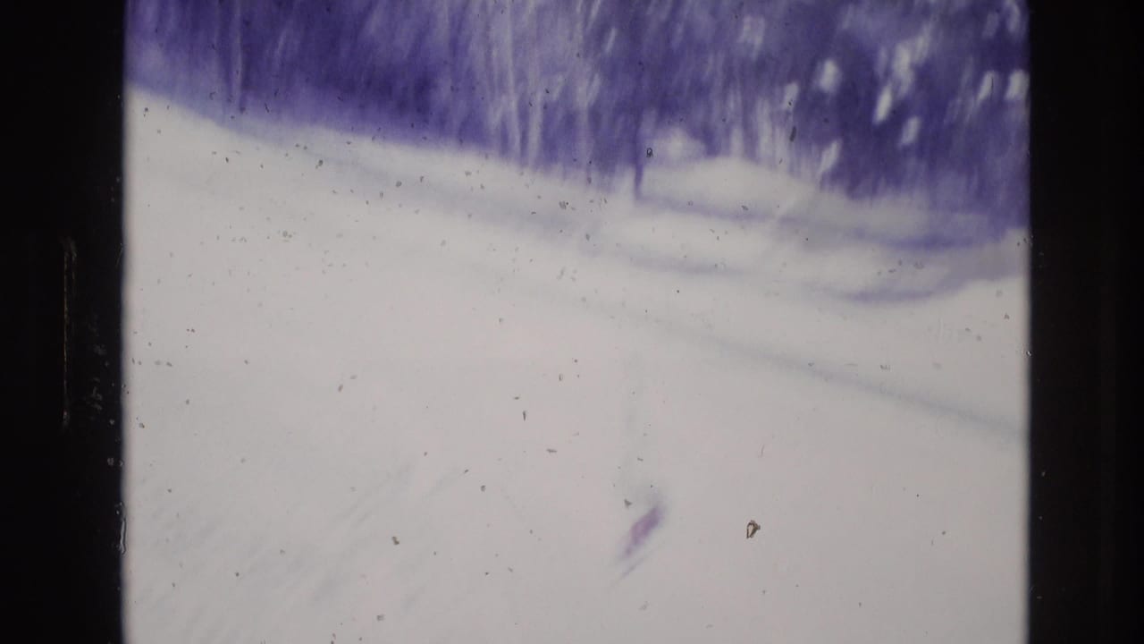 A soft, faded 8mm view of a snow-covered slope and treeline in Vail, Colorado, supported by the clip metadata as 1974 ski resort footage.