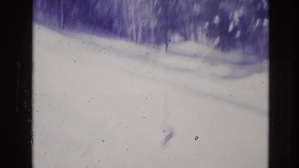 A soft, faded 8mm view of a snow-covered slope and treeline in Vail, Colorado, supported by the clip metadata as 1974 ski resort footage.