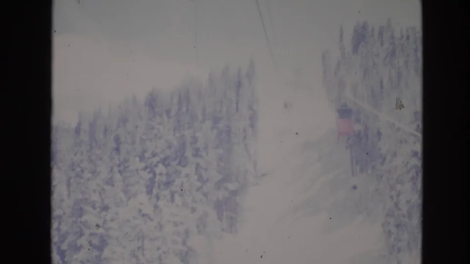 A faded 1974 Vail 8mm view shows ski-lift cable lines above snowy evergreens, with a small lift or building element near the right edge of the frame.