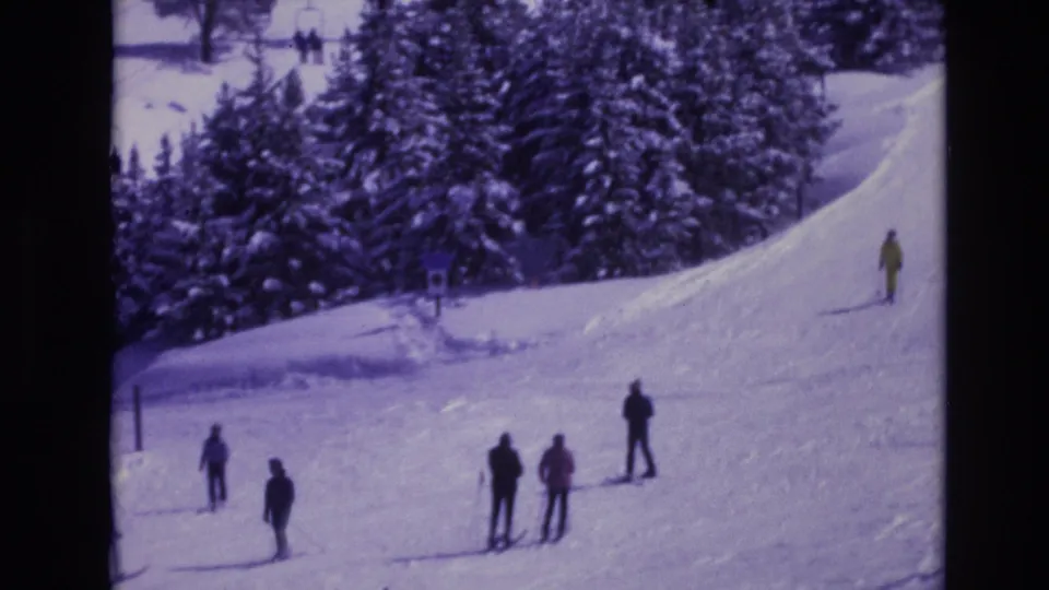 1974 Vail, Colorado 8mm frame with scattered skiers and small groups on a snowy slope, rendered with a purple archival color cast.
