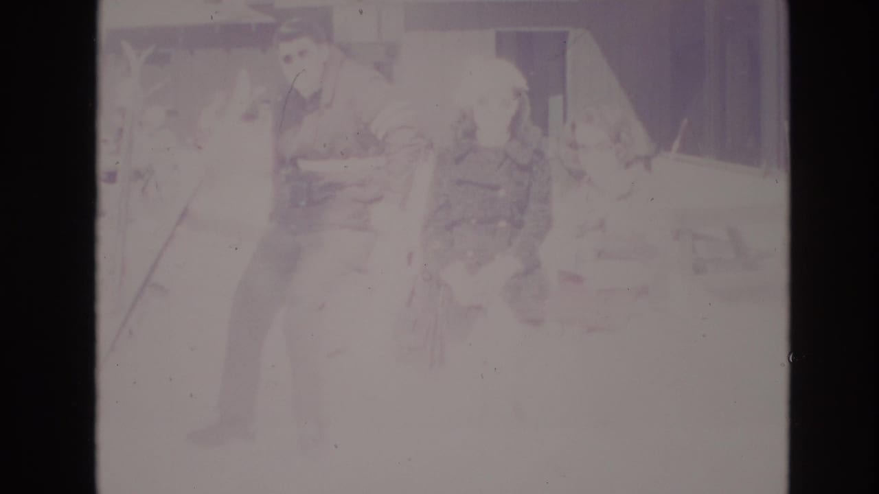 Adults appear to wait together in snowy Vail resort surroundings, with faded 8mm color and a building facade behind them.