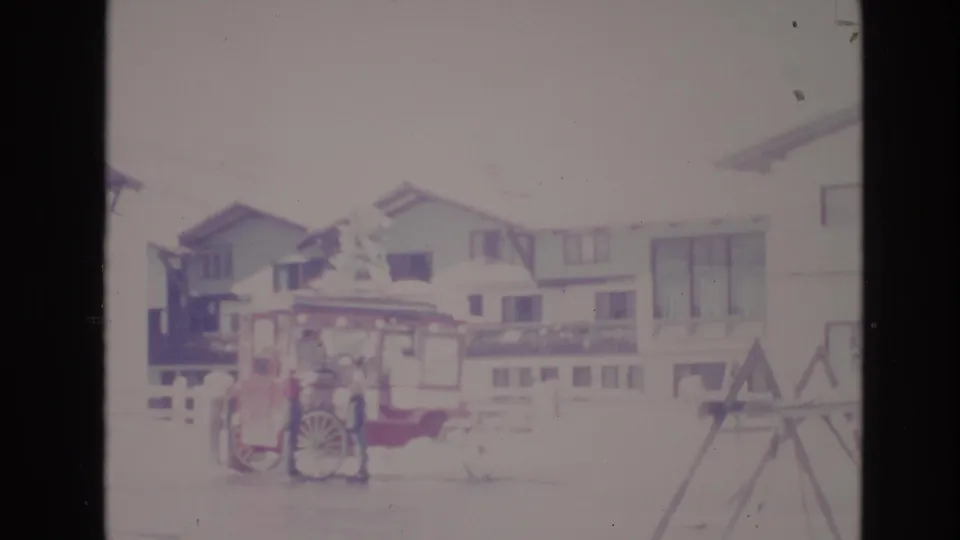 Final 1974 Vail, Colorado 8mm frame showing the red cart near snowy lodge buildings, with a faint foreground structure at right and washed winter exposure.
