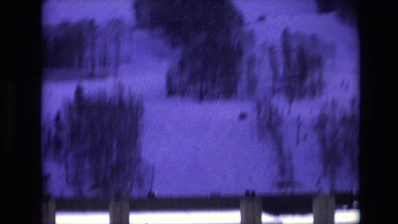 Purple-shifted 8mm frame from Vail, Colorado in 1974 showing a snowy slope with scattered trees and visible film gate edges.