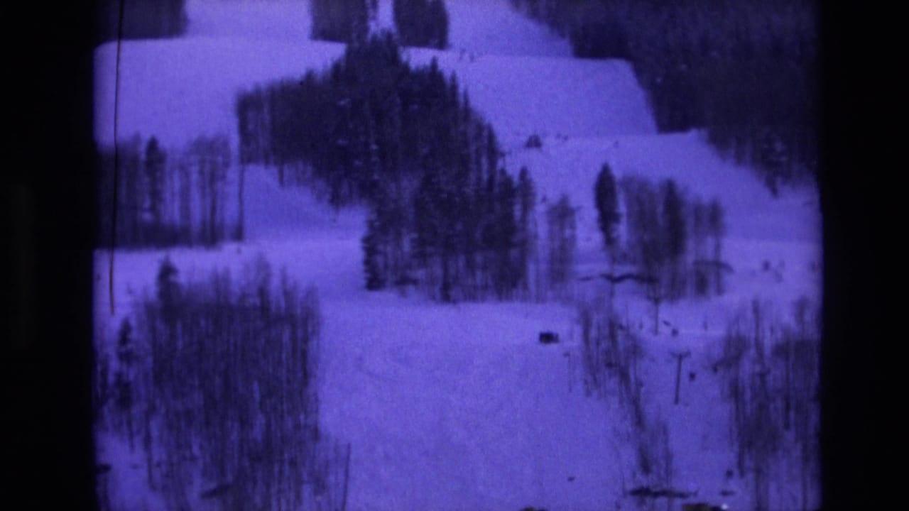 1974 Vail-area home-movie frame showing a snow-covered hillside broken by evergreen stands and distant dark shapes.