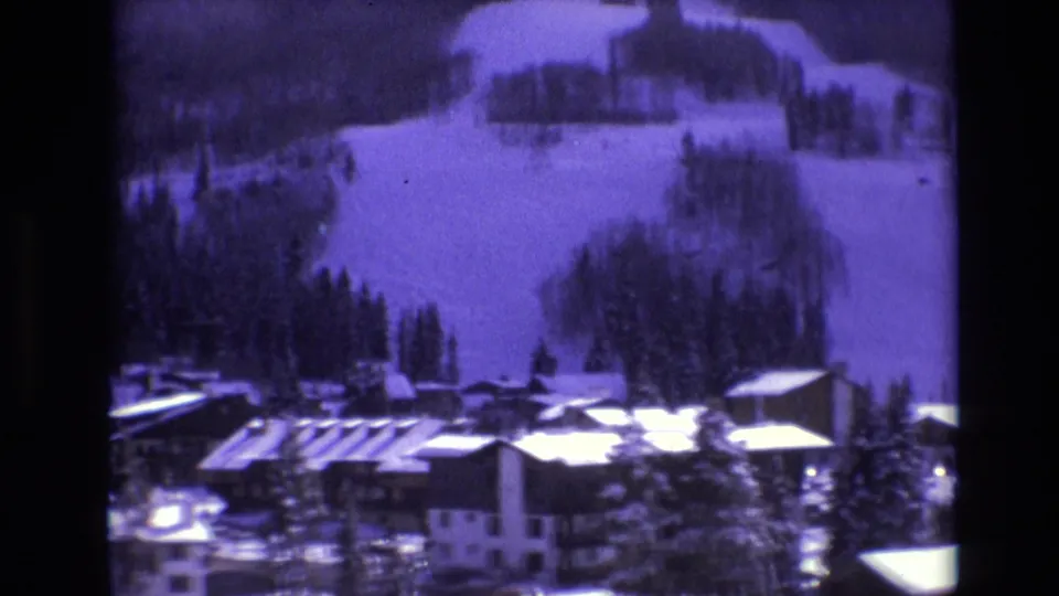 1974 Vail, Colorado home-movie view of alpine-style buildings, evergreen trees, and broad snowy slopes in a winter resort setting.