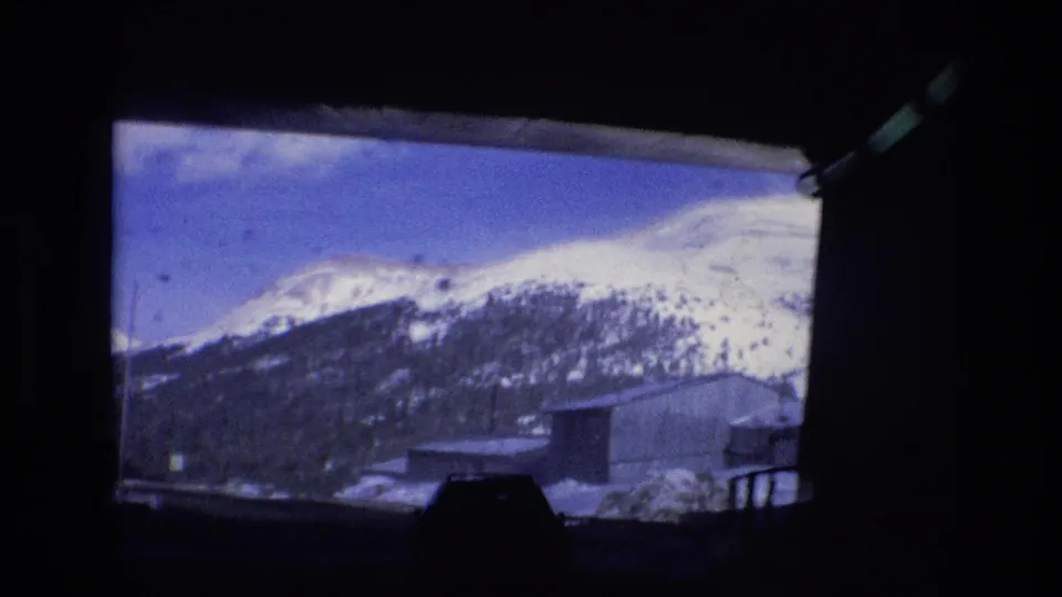 The view opens to snow-covered mountain slopes, roadside structures, and blue sky after the tunnel in the 1974 Vail footage.