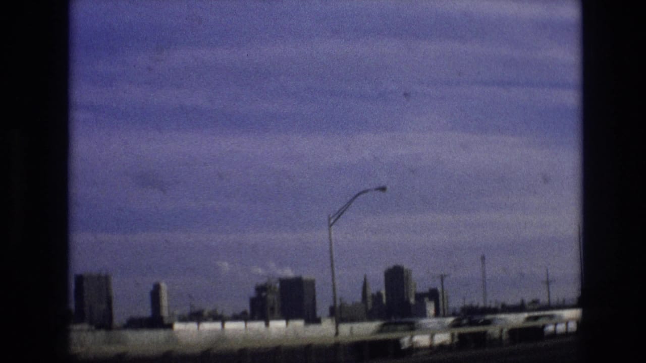 Distant city skyline beyond a highway barrier under a blue sky.