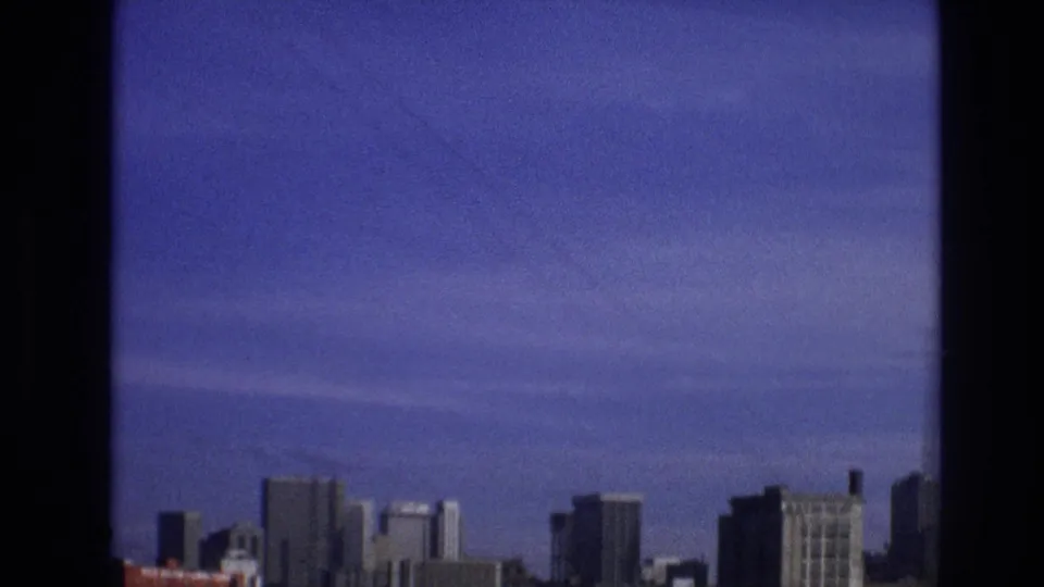 A distant skyline and open sky appear beyond a dark vertical window frame in this purple-tinted 1974 8mm travel view identified as Vail, Colorado.