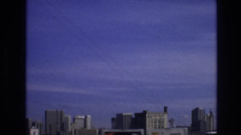 The frame shows a distant line of buildings under a broad purple-blue sky, consistent with the supplied 1974 Vail, Colorado home-movie metadata.