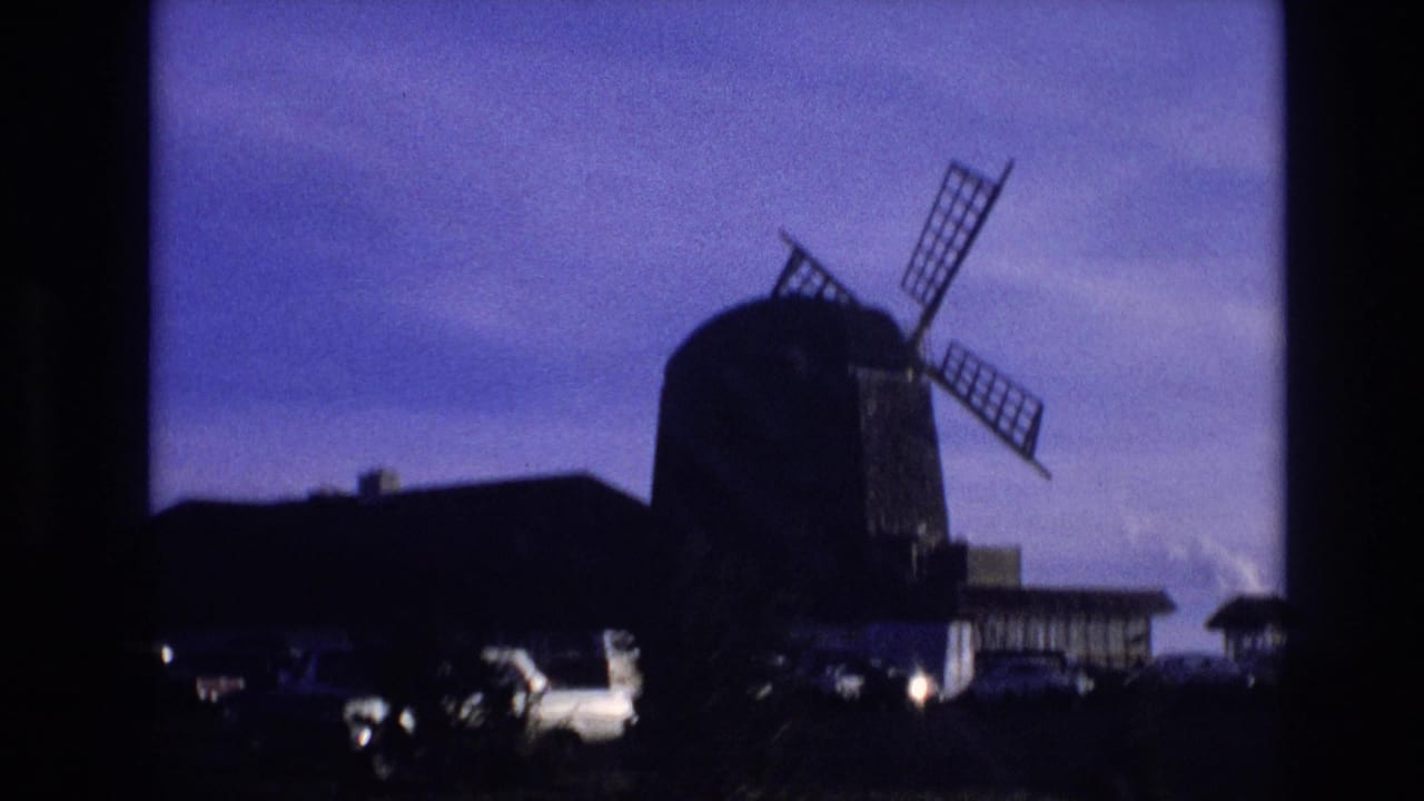 Windmill and parked cars seen from a moving viewpoint.