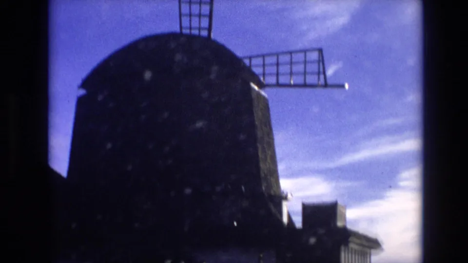 Final Vail travel frame showing the windmill filling much of the view, with blades silhouetted against a blue-purple sky and low structures below.