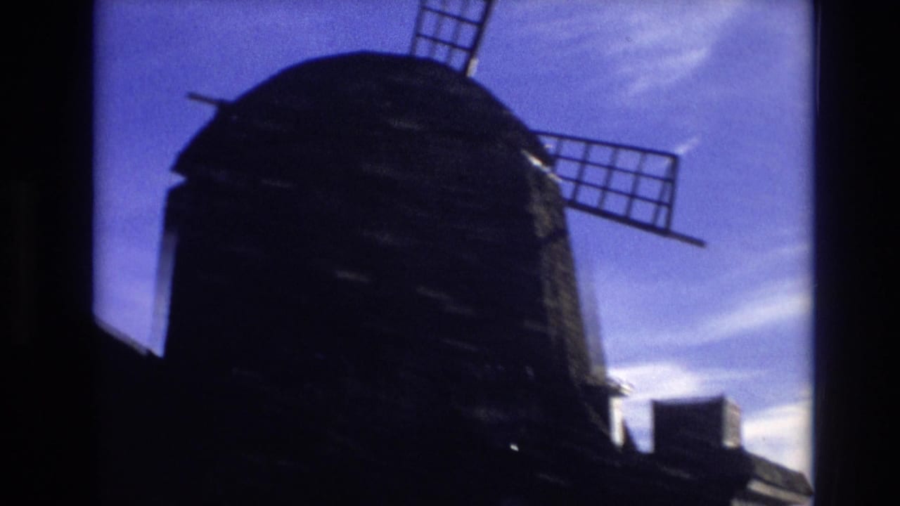 Dark windmill structure with blade arms crossing the sky.