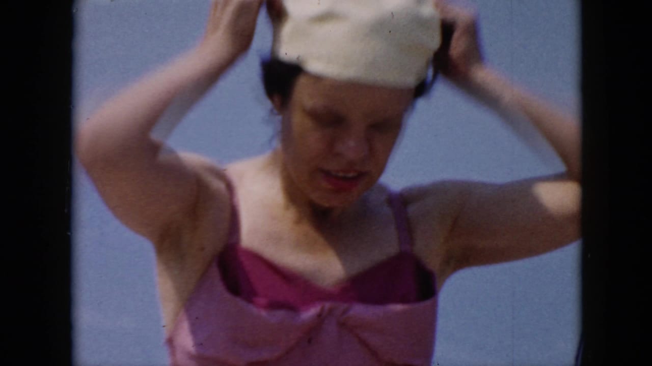 Closer view of a woman adjusting a white swim cap outdoors.