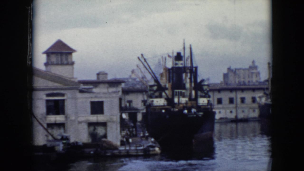 Large ship stern and harbor buildings framed by dark film edges.