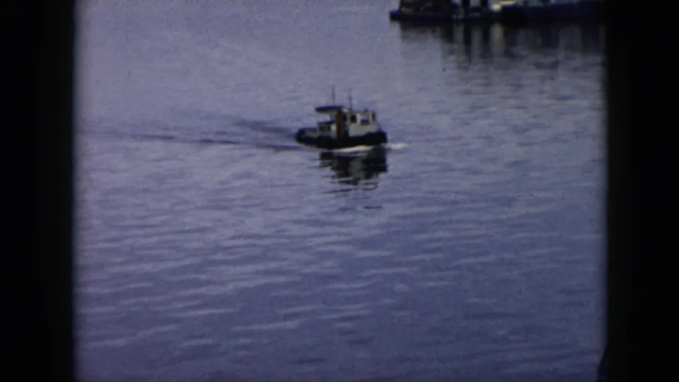1956 Cuba 8mm view of a small motorized boat passing near a waterfront pier, with rippled water and visible film-frame borders.
