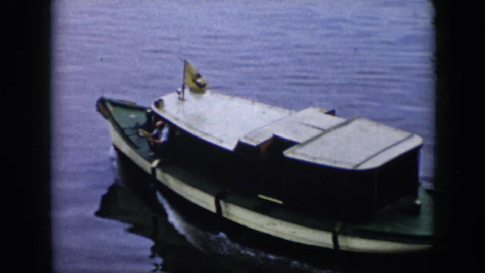 1956 Cuba 8mm frame showing the small cabin motorboat from above, with a visible wake and a man near the bow.