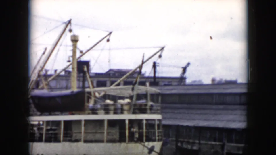 1956 Cuba home-movie frame showing a docked vessel, cranes, railings, and low waterfront buildings in a port setting.