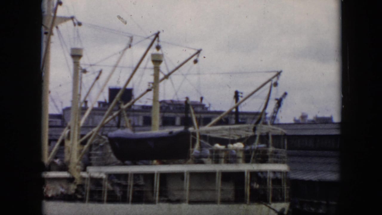 Docked ship and harbor cranes framed by dark film borders.
