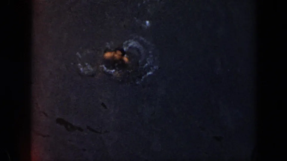 1956 Cuba frame with a swimmer surfacing in dark water, surrounded by ripples and softened by grain and low exposure.