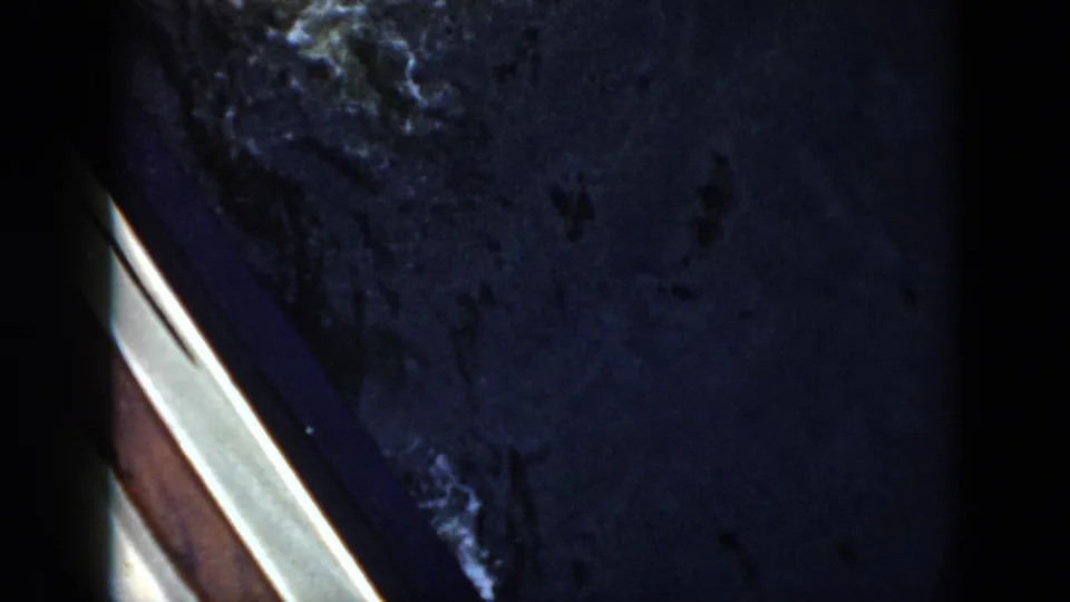 1956 Cuba frame showing disturbed dark water and splash trails, with the swimmer mostly out of view and a bright diagonal frame edge.