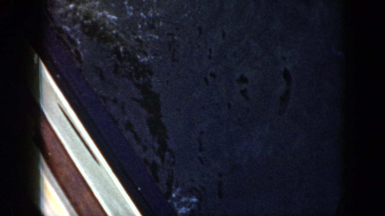 Dark blue pool water in a 1956 Cuba 8mm home-movie frame, with a pale pool or deck edge at left.