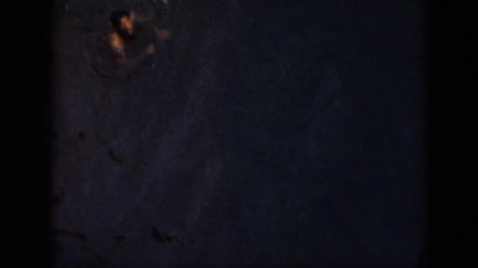 1956 Cuba 8mm frame showing dark water and a distant swimmer silhouette under very low light.