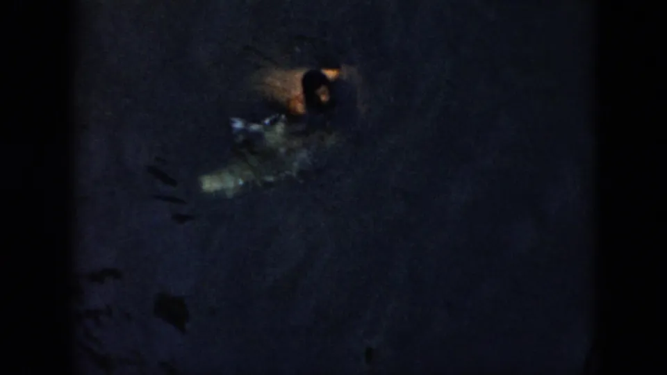1956 Cuba 8mm frame with a swimmer partly visible in dark water, surrounded by ripples and splash highlights.