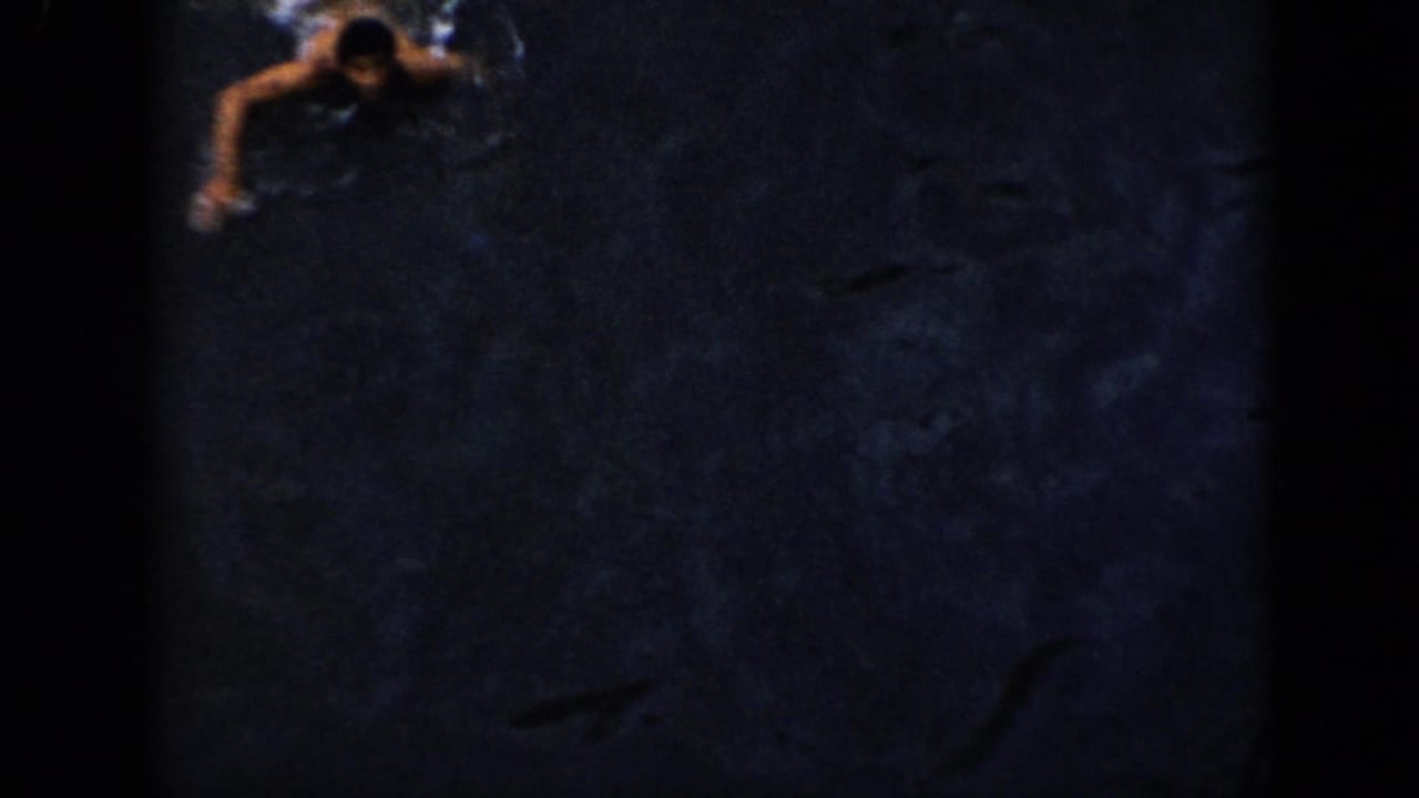 Grainy 1956 Cuba 8mm frame with a swimmer near the upper edge of dark open water.