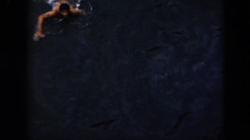 Grainy 1956 Cuba 8mm frame with a swimmer near the upper edge of dark open water.