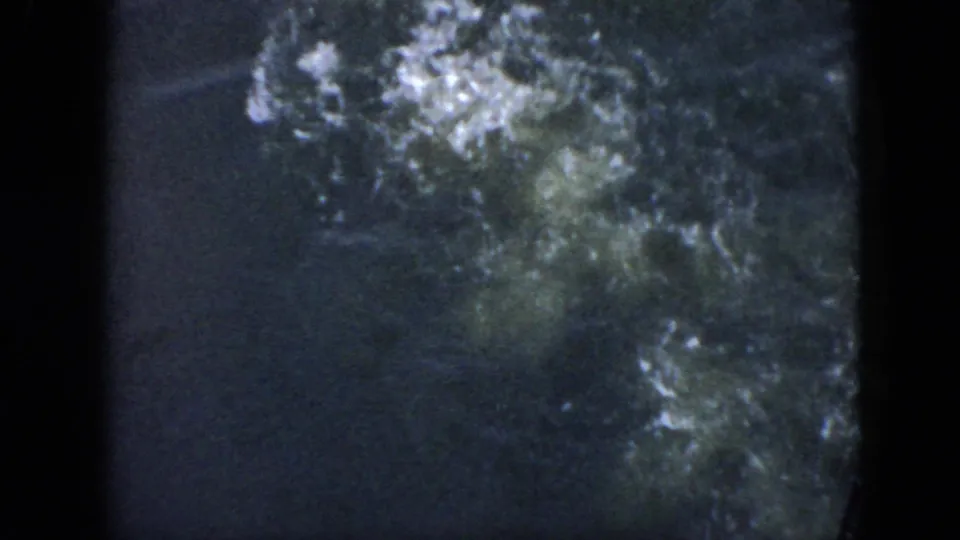 1956 Cuba 8mm frame showing dark water with white bubbles spreading after a swimmer dives below the surface.