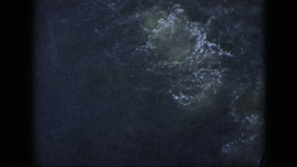 1956 Cuba 8mm frame with disturbed dark water and pale bubbles where the swimmer has gone underwater.