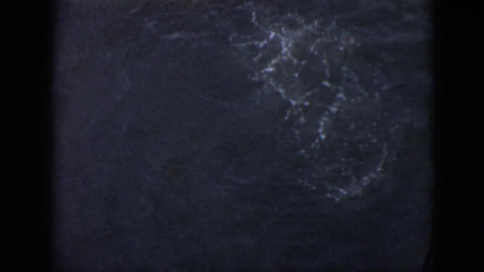 1956 Cuba home-movie frame showing fading underwater bubbles and ripples across a dark water surface.