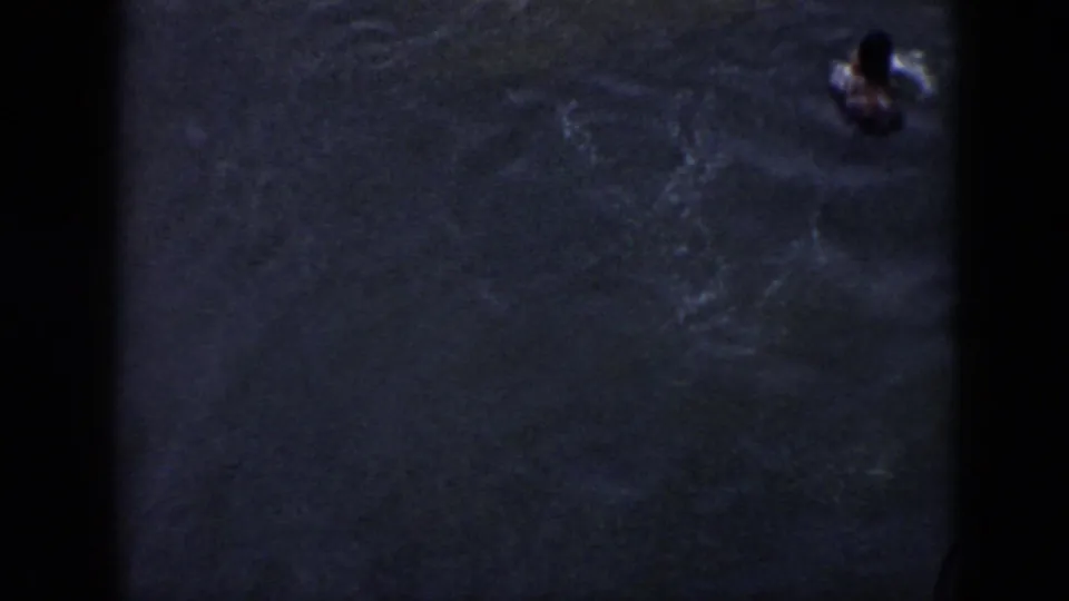 1956 Cuba 8mm frame showing a swimmer resurfacing at the edge of the shot in dark rippling water.