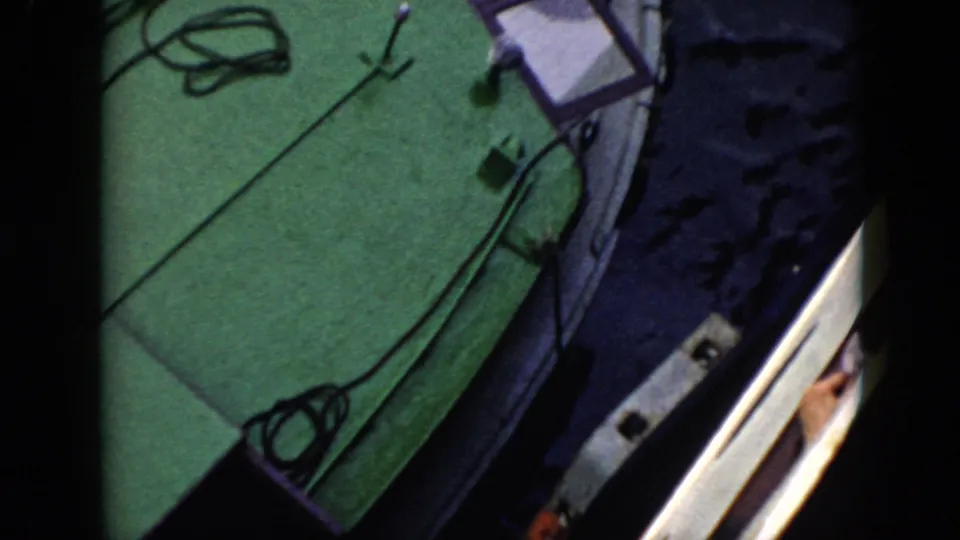 A green boat deck, rope, pole, rail, and water appear in a 1956 Cuba home-movie frame.