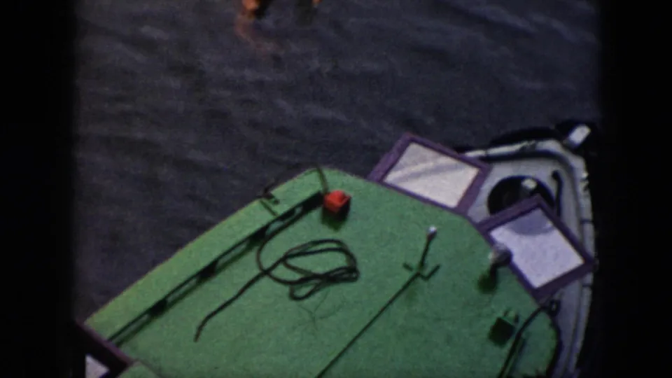The small boat remains in view from above, with its green deck, coiled rope, railings, and surrounding water visible in the 1956 Cuba footage.