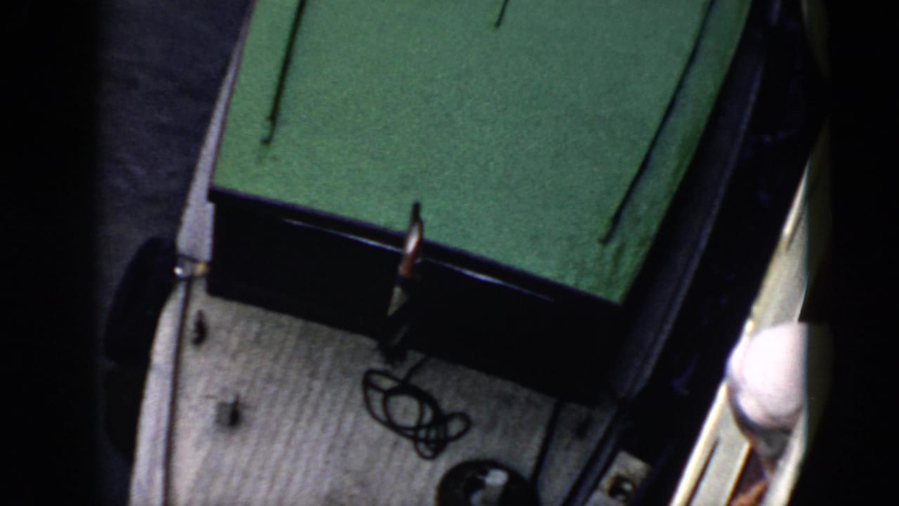 1956 Cuba home-movie frame showing a white boat with a green roof near a jetty, seen from above.