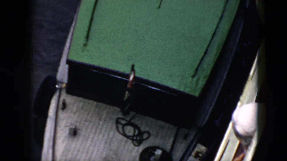 1956 Cuba home-movie frame showing a white boat with a green roof near a jetty, seen from above.
