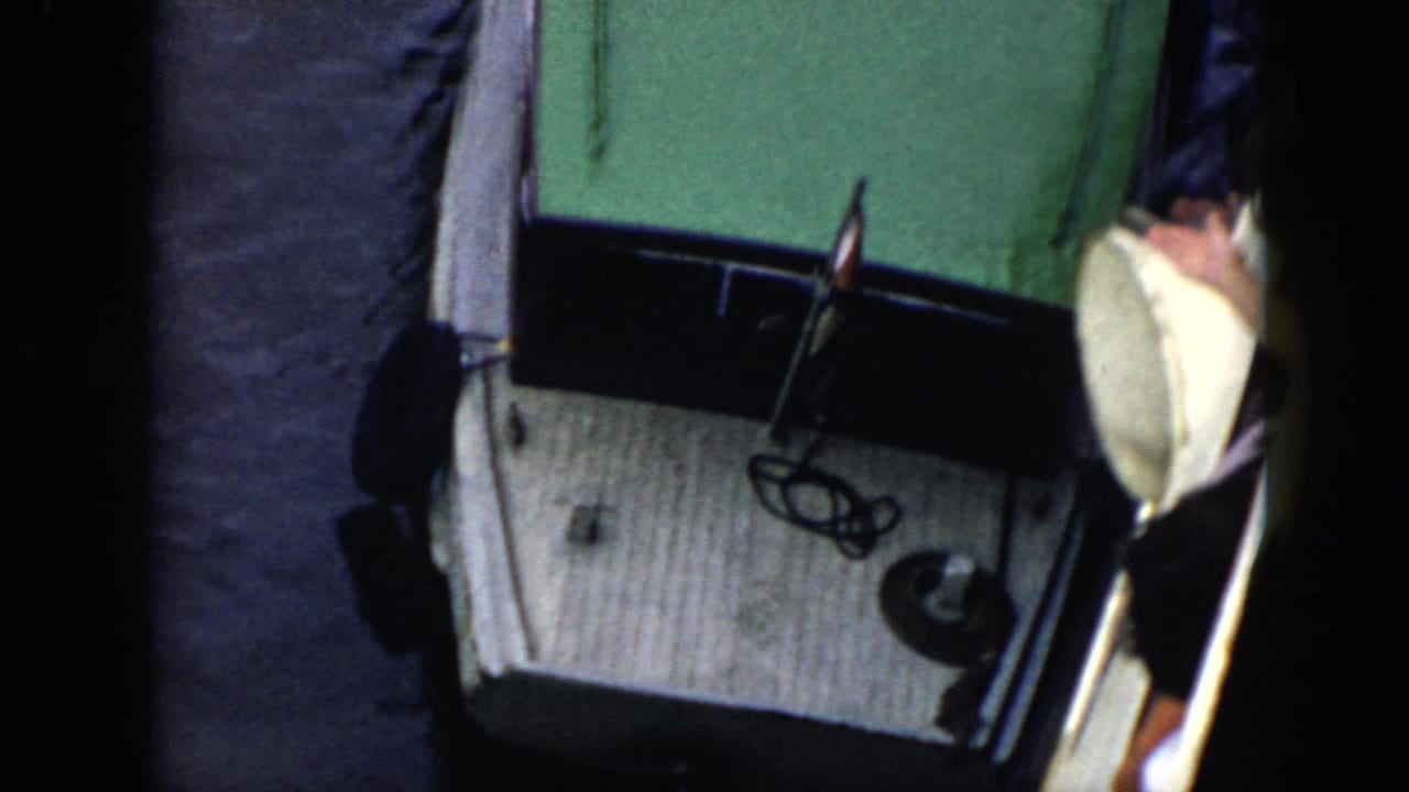 White boat with green roof at the side of a jetty with a partial person visible.