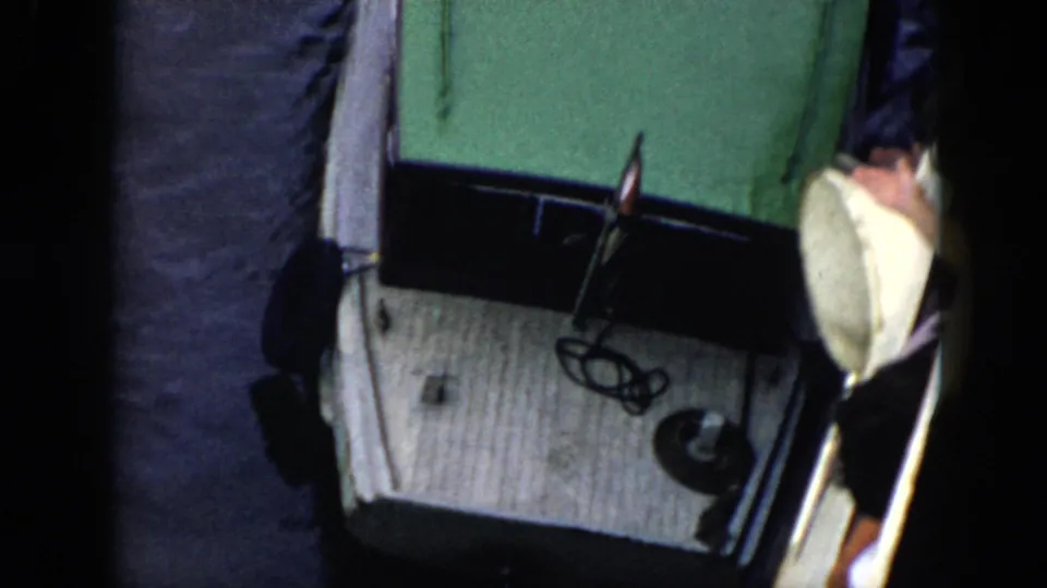 1956 Cuba frame of the green-roofed white boat beside the jetty, with a partial person at the right edge.
