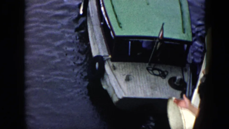 1956 Cuba home-movie view of the white boat beginning to leave the jetty, with a partial person and white object at right.