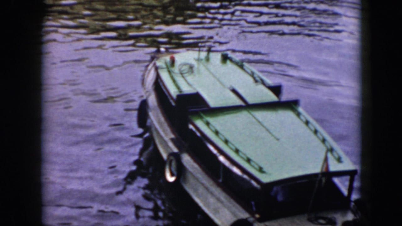 1956 Cuba 8mm frame showing a small green-deck boat on calm rippling lake water, seen from above.