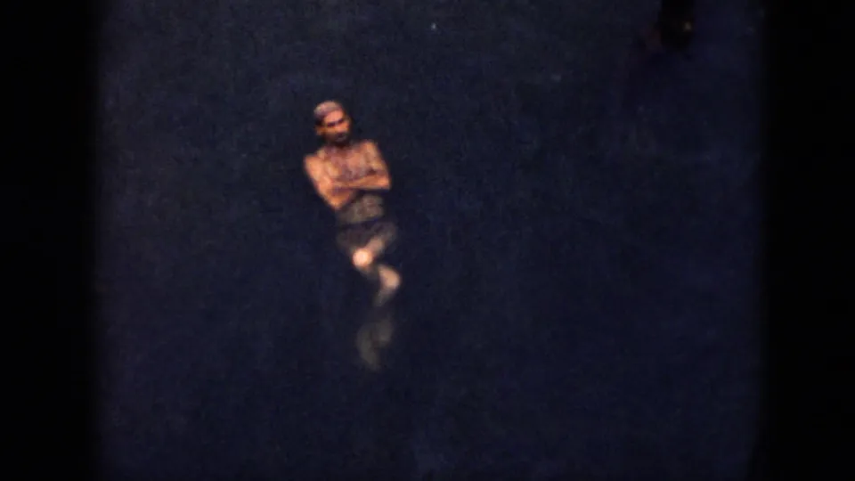 1956 Cuba home-movie frame with an adult male swimmer floating upright in dark lake water.