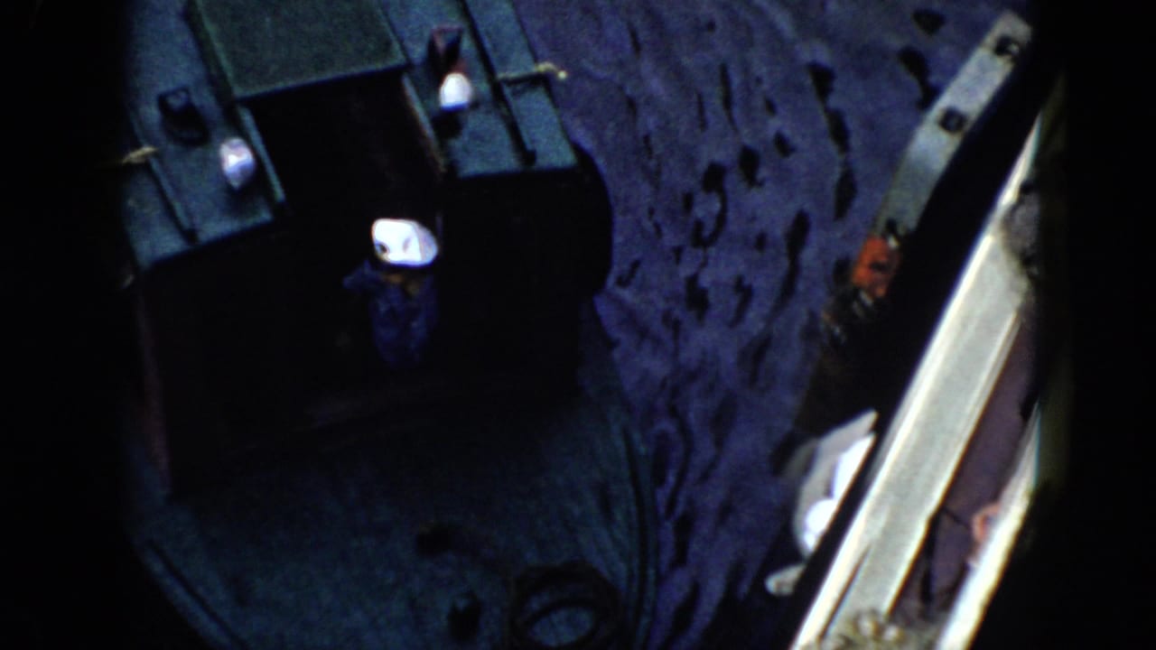 1956 Cuba 8mm frame showing a high-angle night view of dark water, a boat edge, and a person close to the vessel.