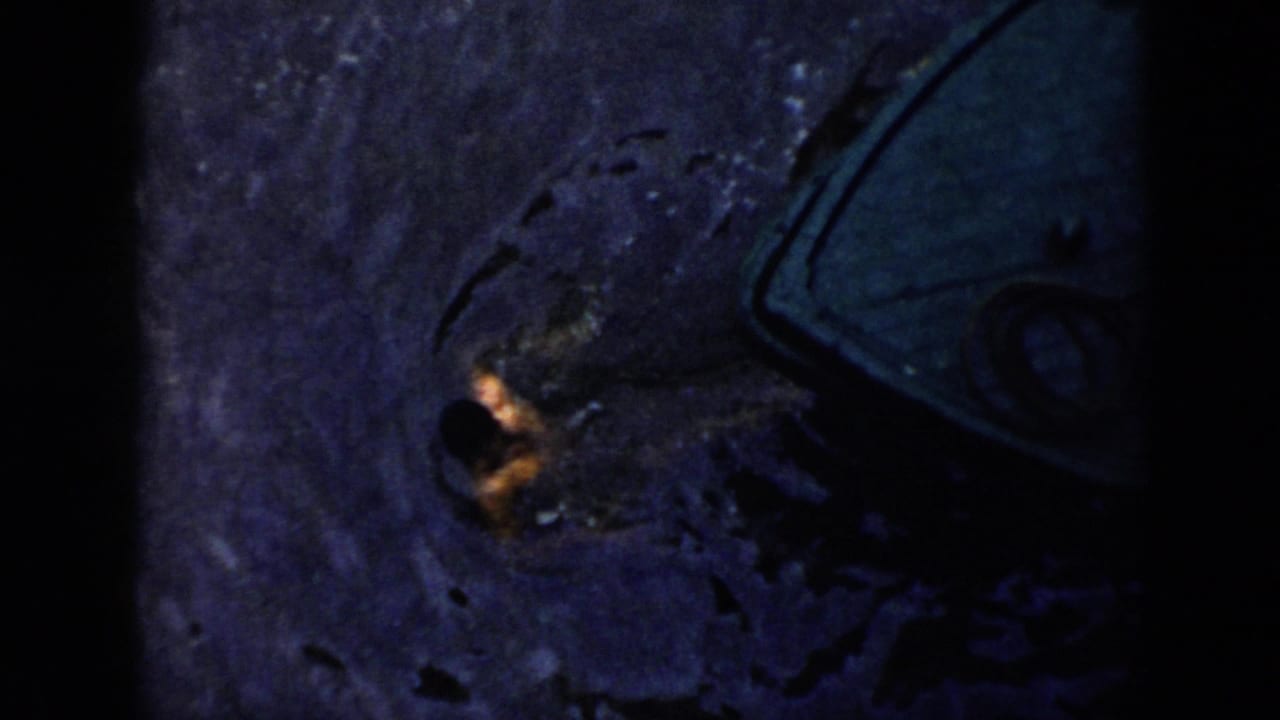 Person partly visible in dark water beside the curved outline of a boat.