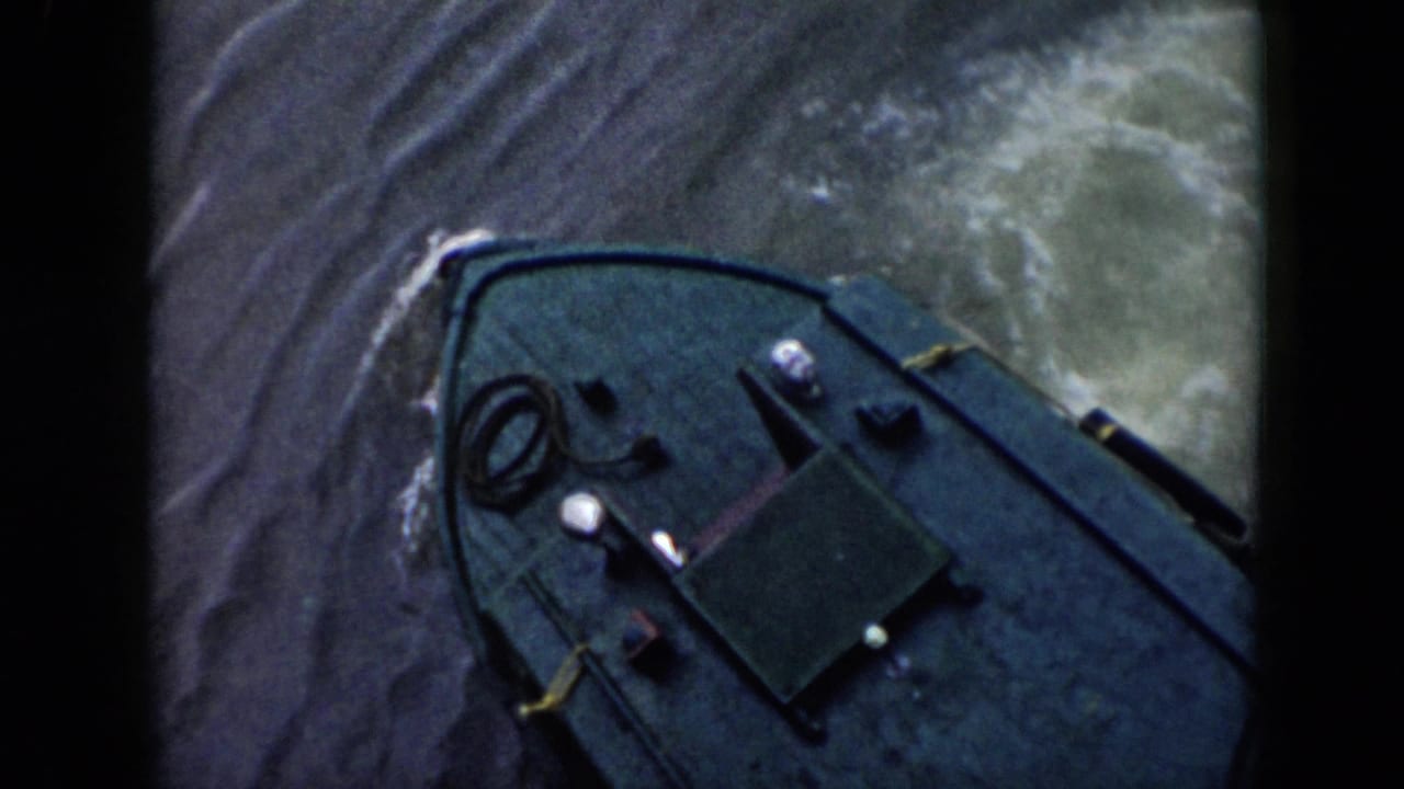 Overhead 8mm view from 1956 Cuba showing the small boat bow, deck fittings, and wake spreading through rippled water.