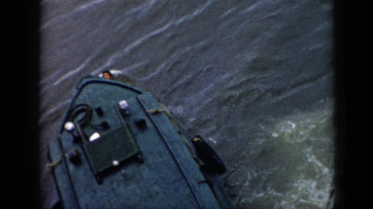 1956 Cuba 8mm frame with the boat bow viewed from above, deck gear visible, and wake spreading across gray-green water.