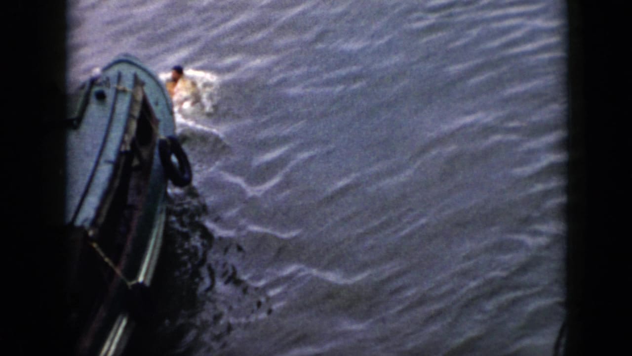 1956 Cuba 8mm frame showing a swimmer in light clothing close to a small boat amid foamy wake.