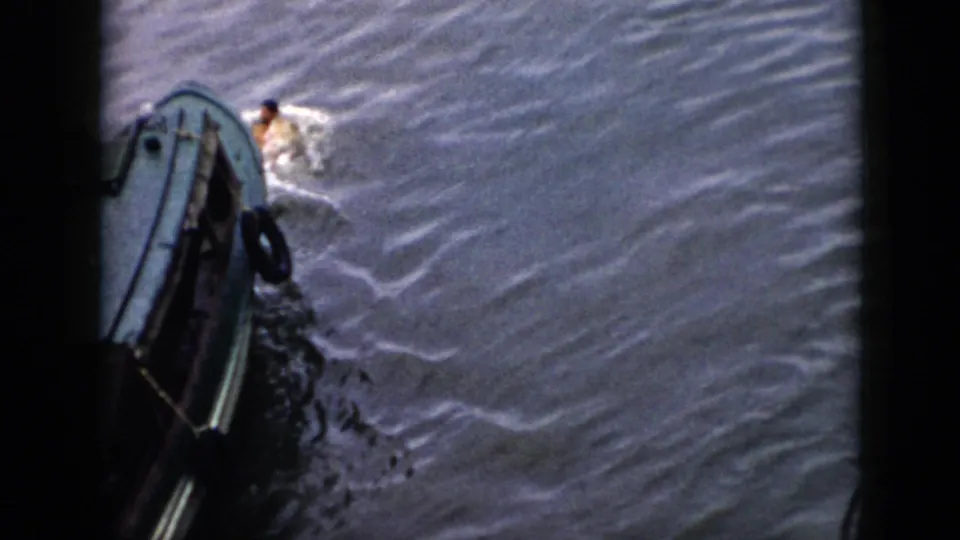 1956 Cuba 8mm frame showing a swimmer in light clothing close to a small boat amid foamy wake.