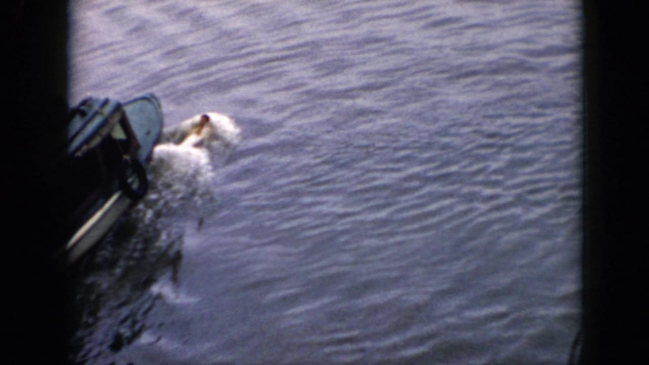 1956 Cuba 8mm frame showing a small motorboat on calm water with a swimmer alongside and dark edge framing.
