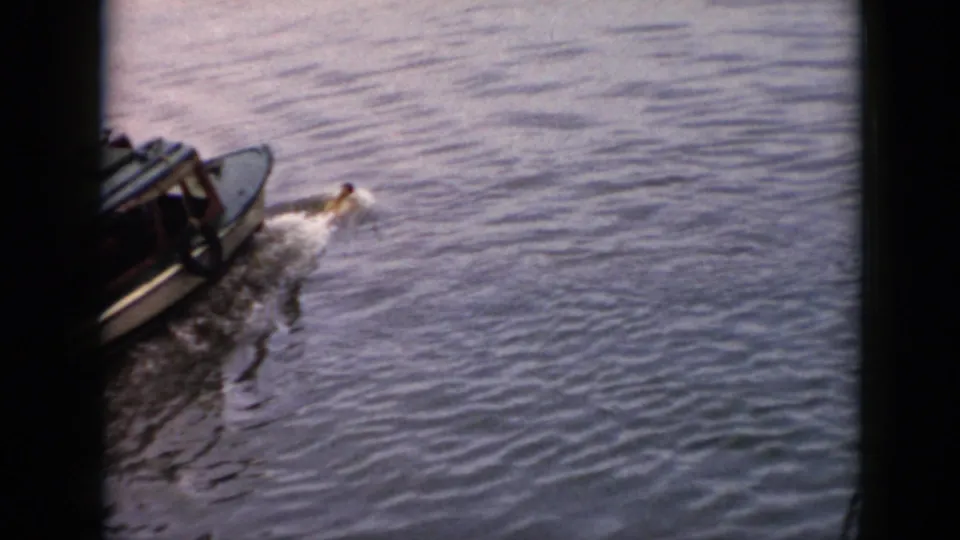 1956 Cuba home-movie frame of a motorboat crossing rippled water while a swimmer remains close beside it.